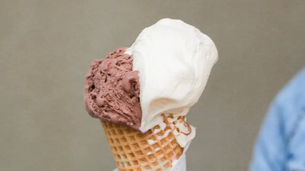 un sujeto sostiene un cono de helado compuesto por una bola de chocolate y una bola de vainilla