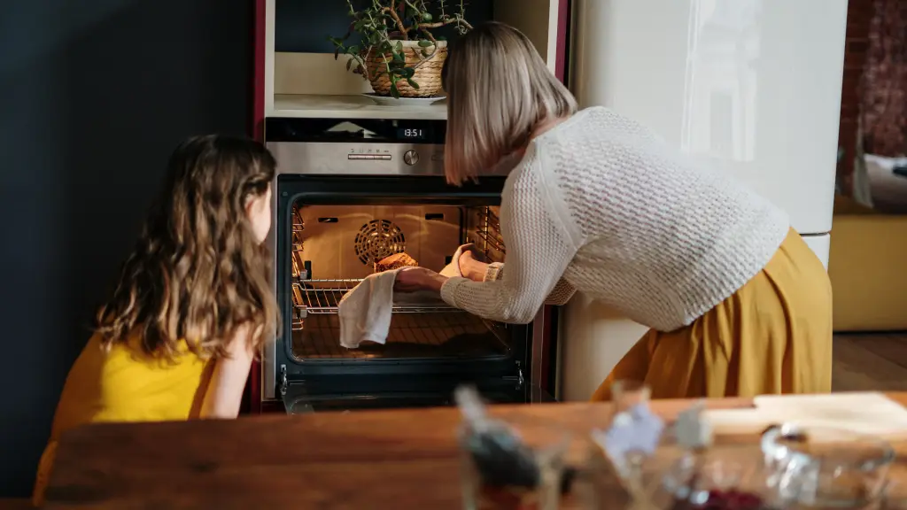 una mujer y su hija metiendo comida al horno